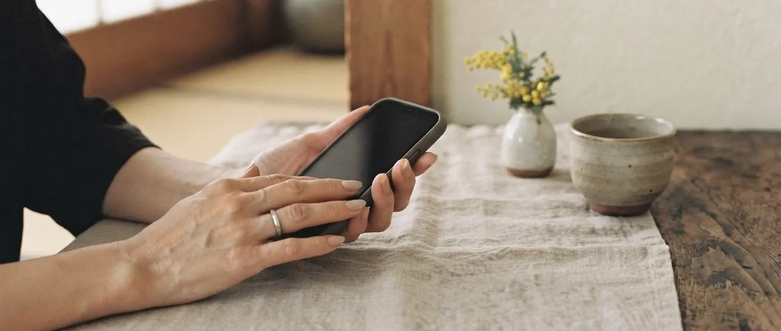和室の机でオーナーがスマートフォンで予約を確かめている手元